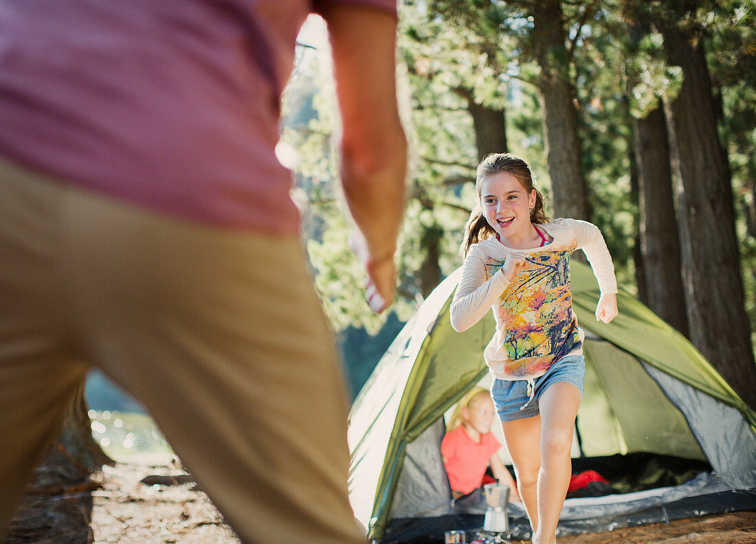 Daughter running to father outside tent in woods