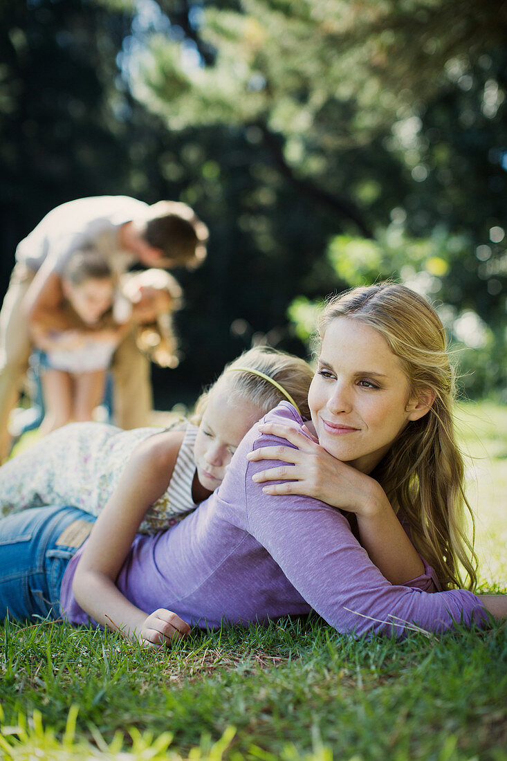 Serene mother and daughter laying in grass