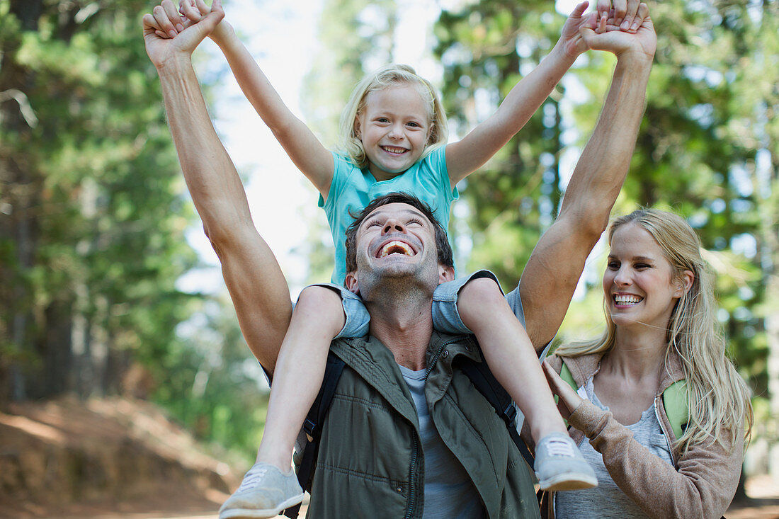 Father carrying daughter on shoulders in woods