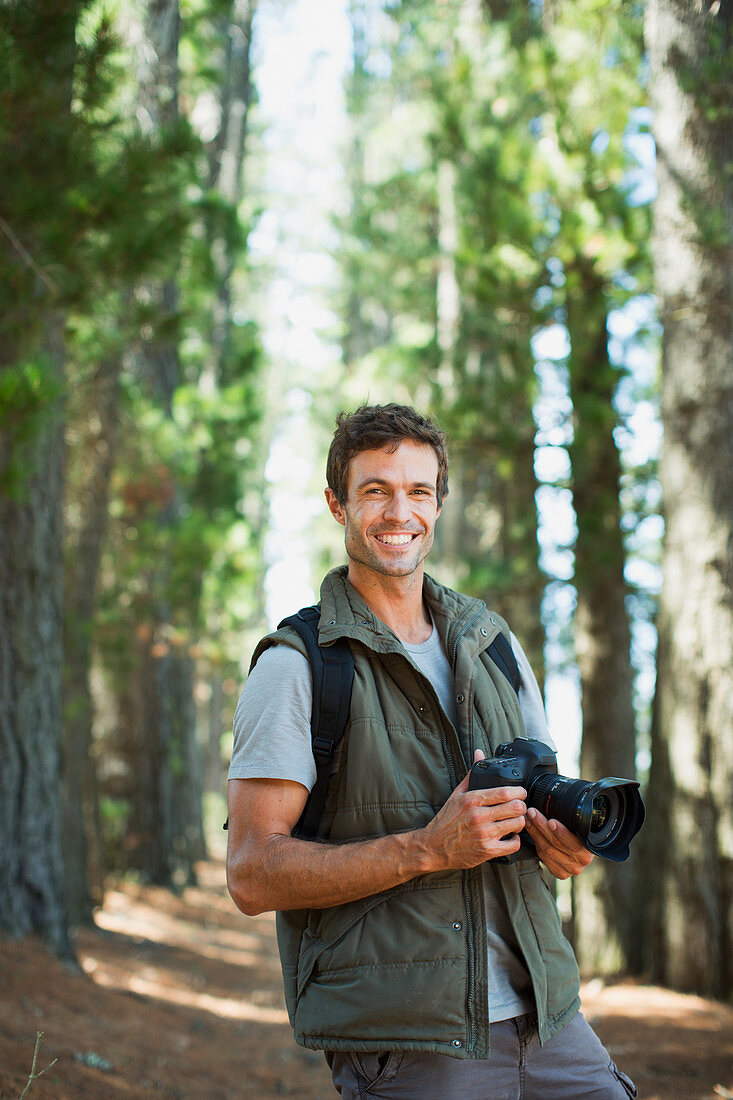 Smiling man with digital camera in woods