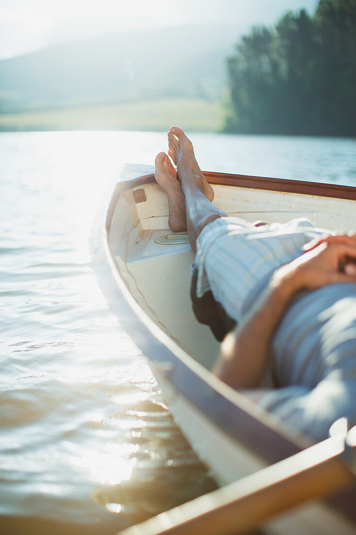 Serene man laying rowboat on calm lake