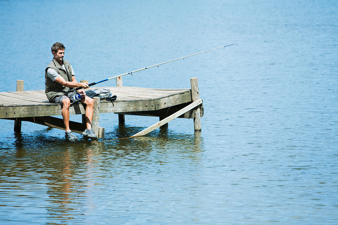 Man fishing from dock over lake