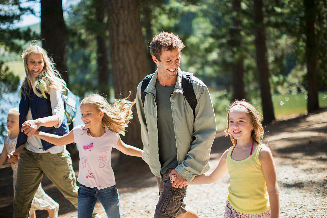 Smiling family holding hands and walking in woods