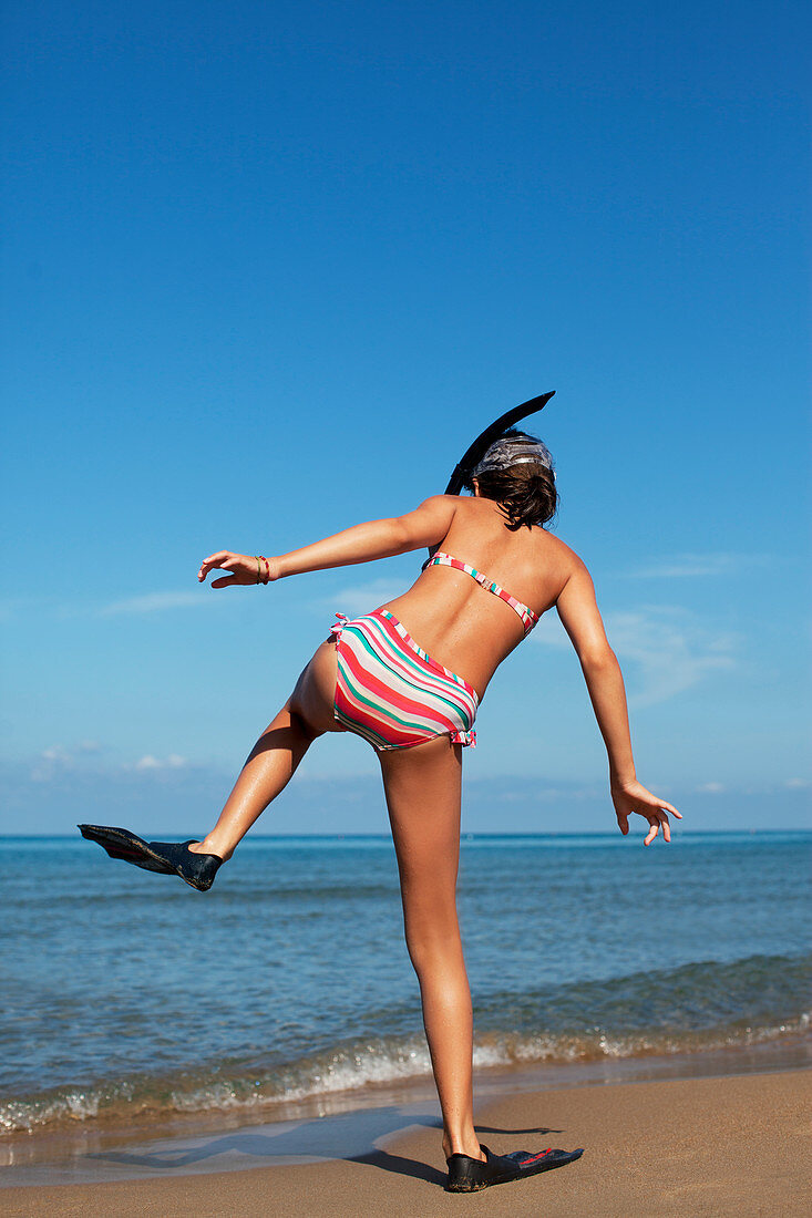 Girl walking on beach with flippers