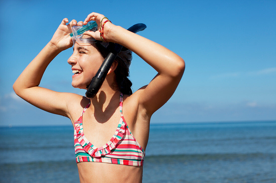 Smiling girl wearing snorkel and goggles on beach