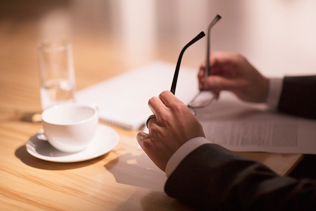 Businessman holding eyeglasses over paperwork