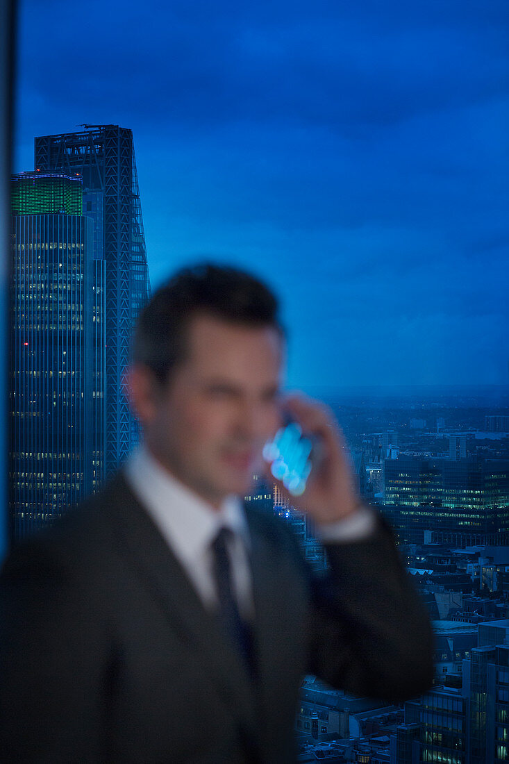 Businessman talking on cell phone at urban window