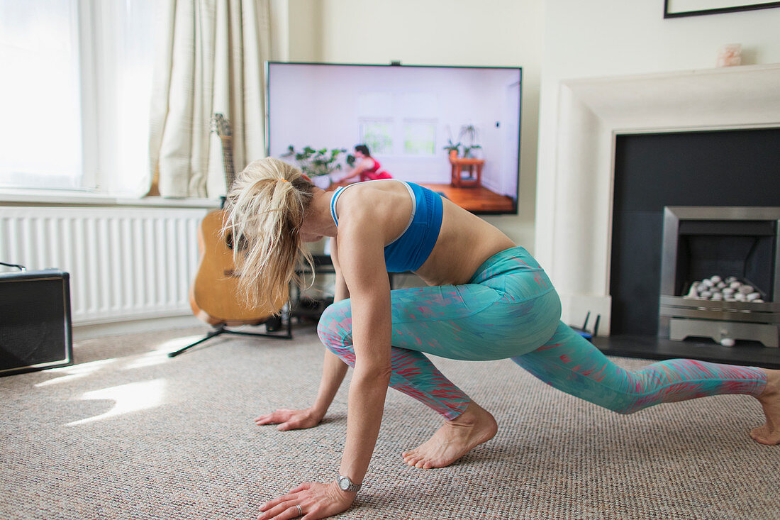 Woman practicing online yoga in living room