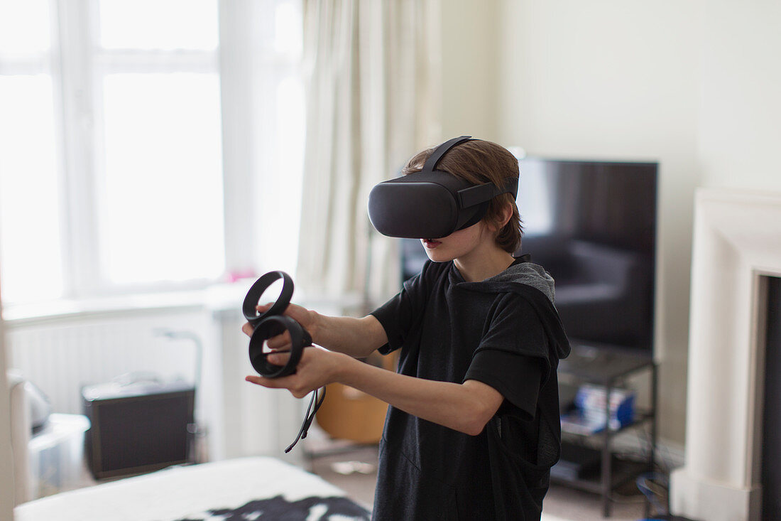 Boy playing video game with VRS goggles in living room