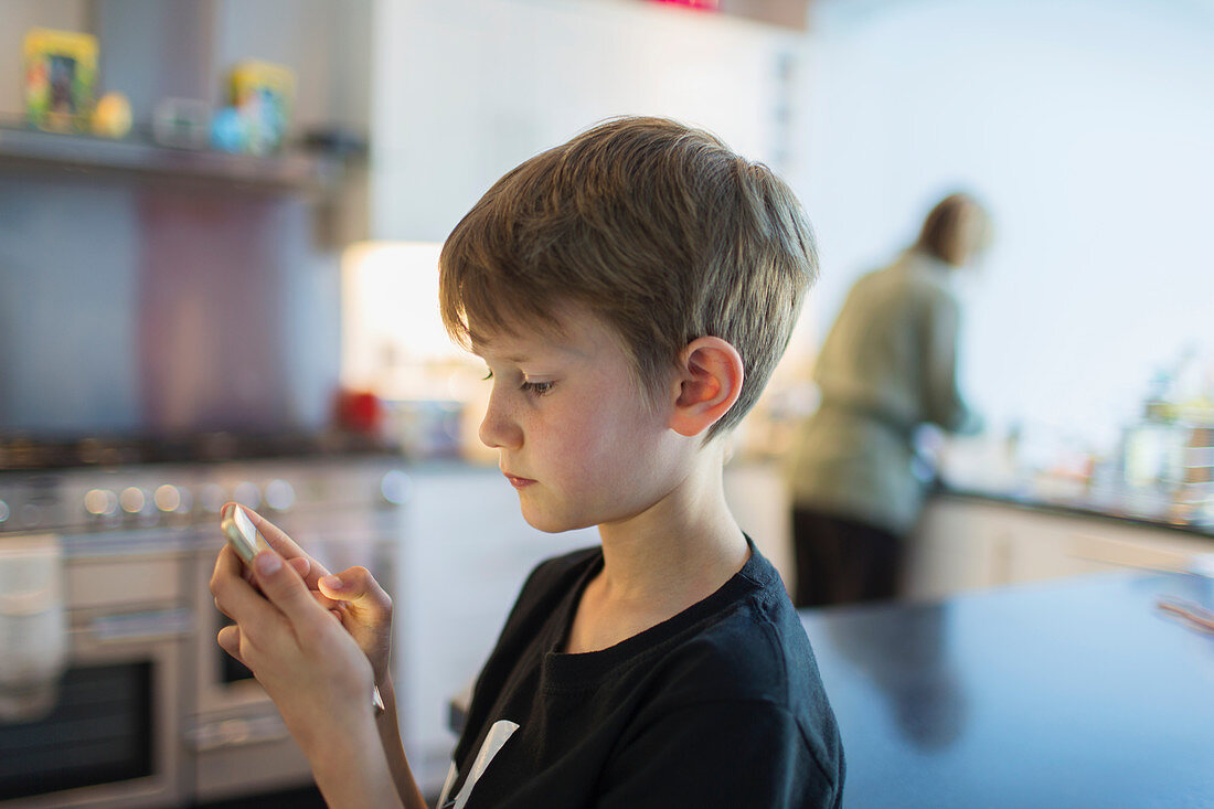Boy using smart phone in kitchen