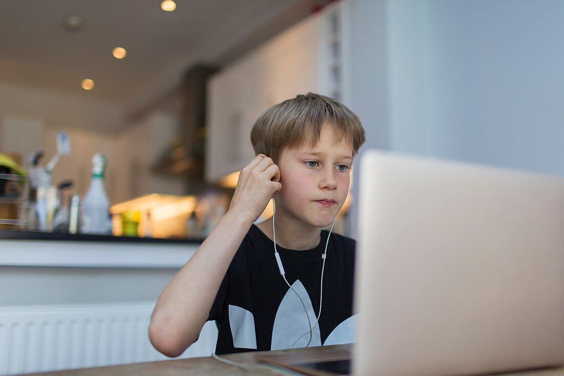 Boy with headphones homeschooling at laptop