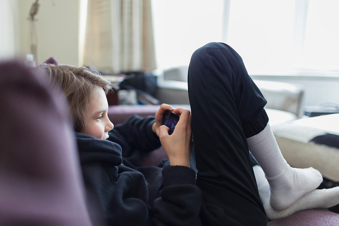 Boy playing video game with smart phone on sofa