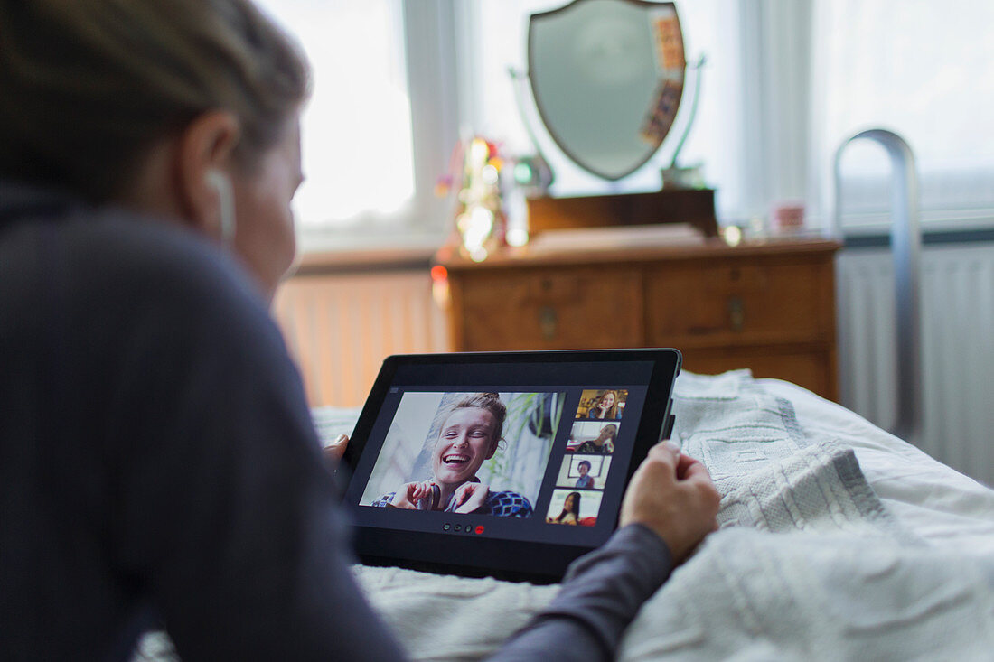 Woman with digital tablet video chatting on bed