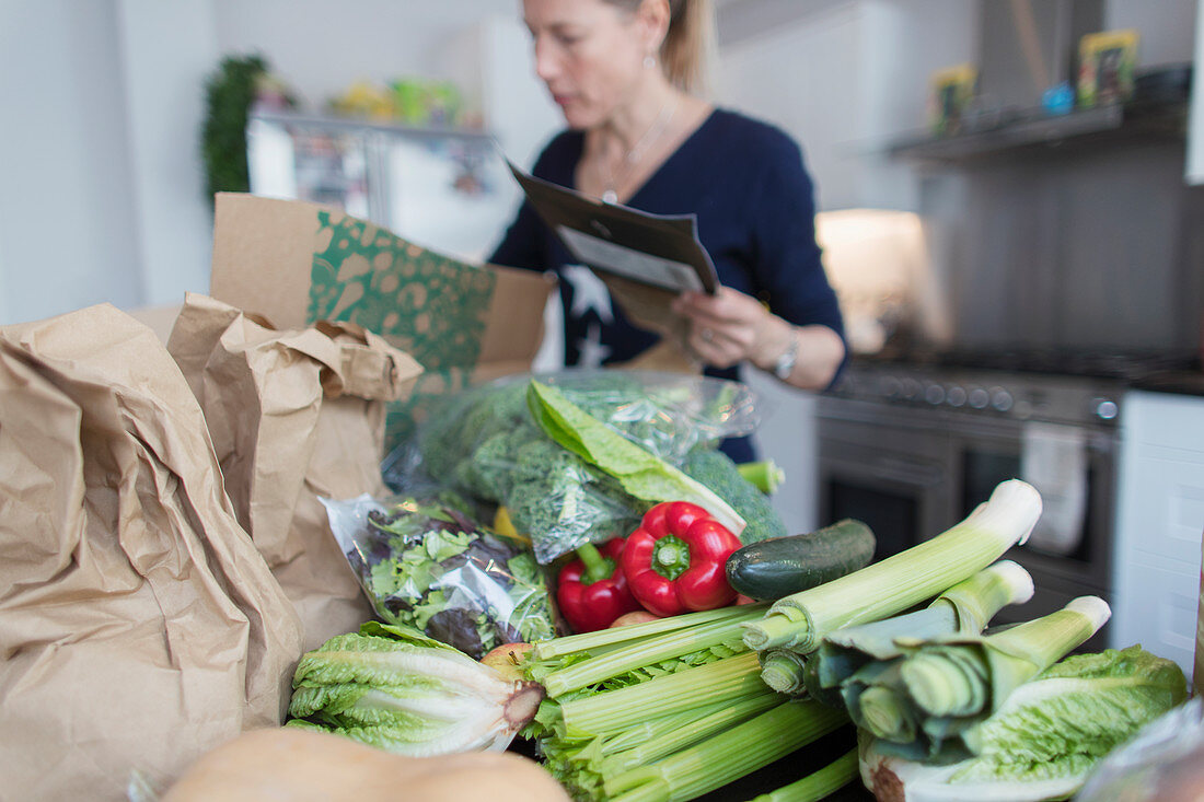 Woman unloading fresh produce from box in kitchen