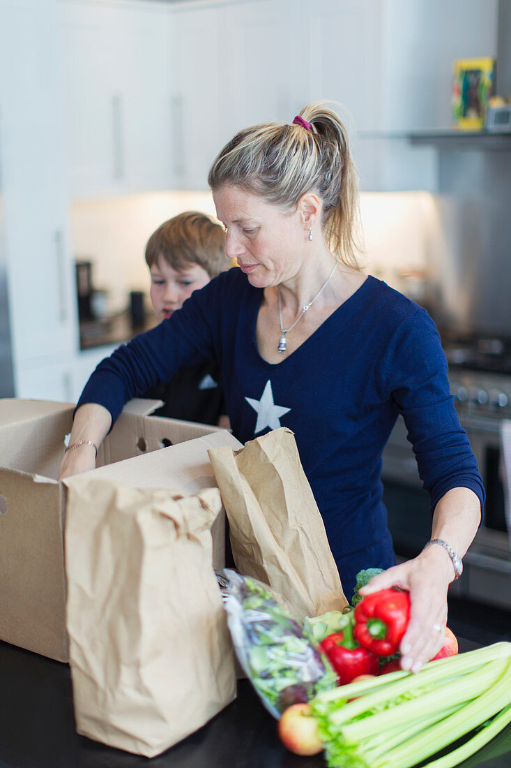 Mother and son unloading fresh produce in kitchen