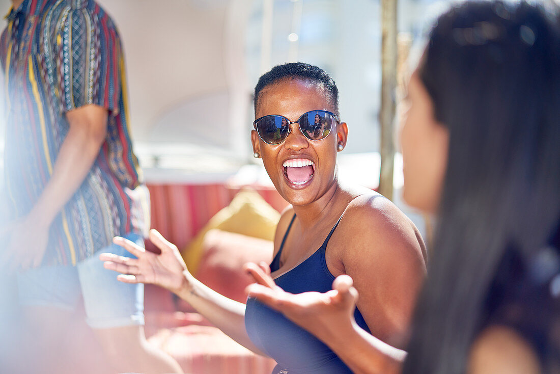 Happy young woman laughing with friends on sunny patio