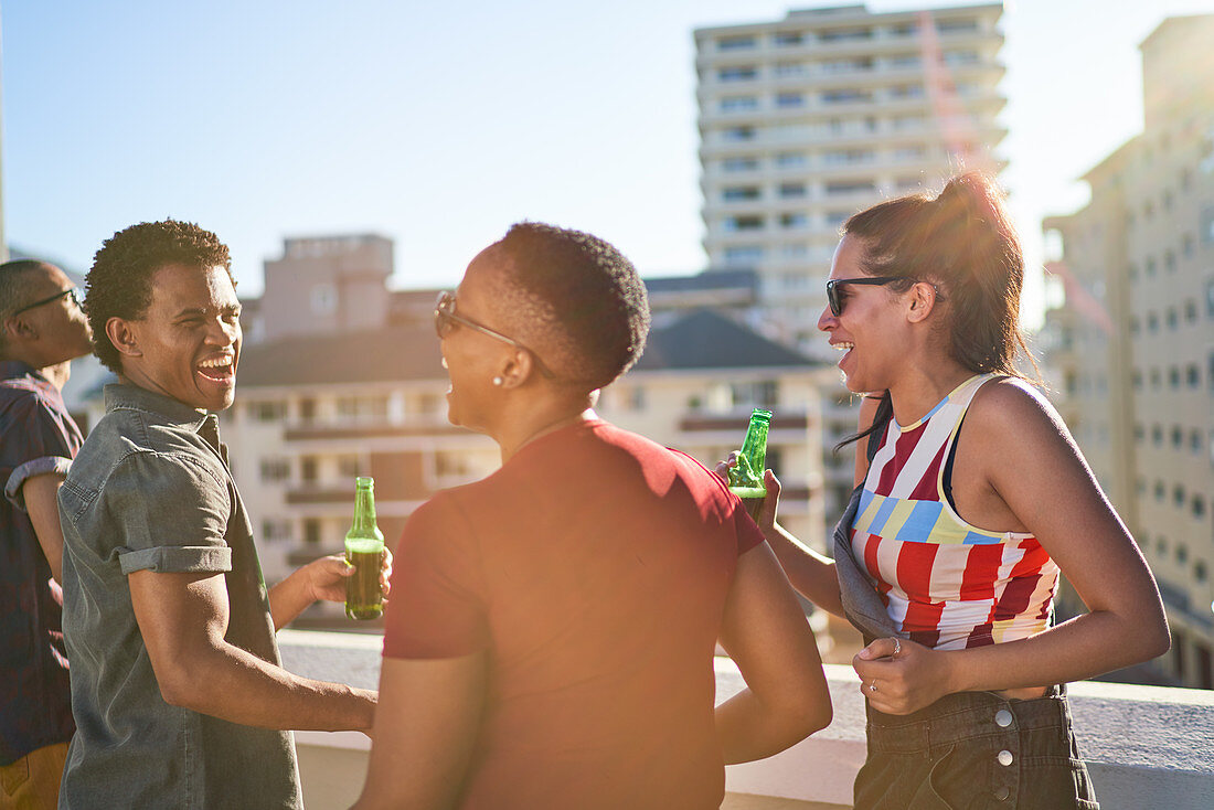 Happy young friends hanging out on sunny rooftop balcony