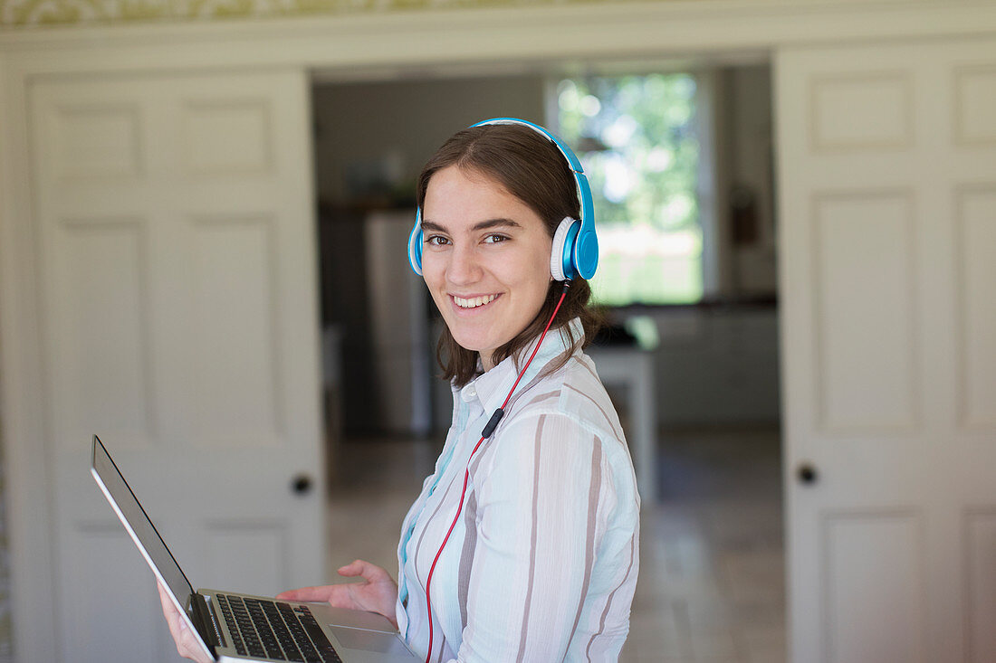 Portrait confident teenage girl with headphones and laptop