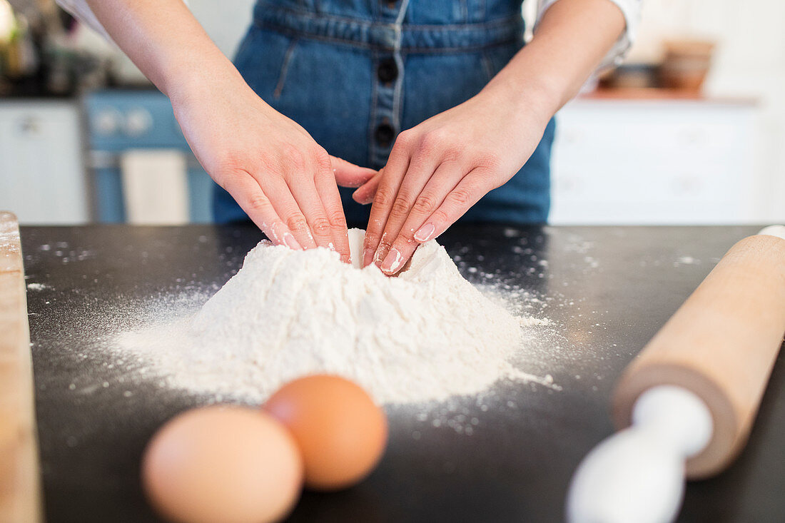 Close up teenage girl making flour nest on kitchen counter