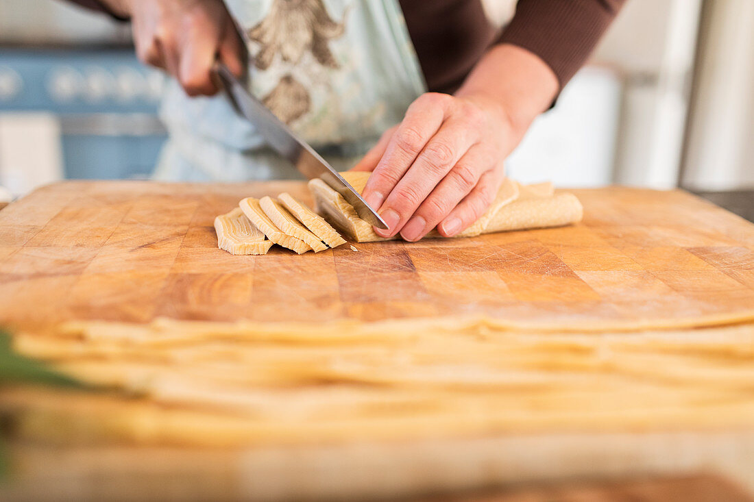 Close up woman cutting fresh homemade dough on cutting board