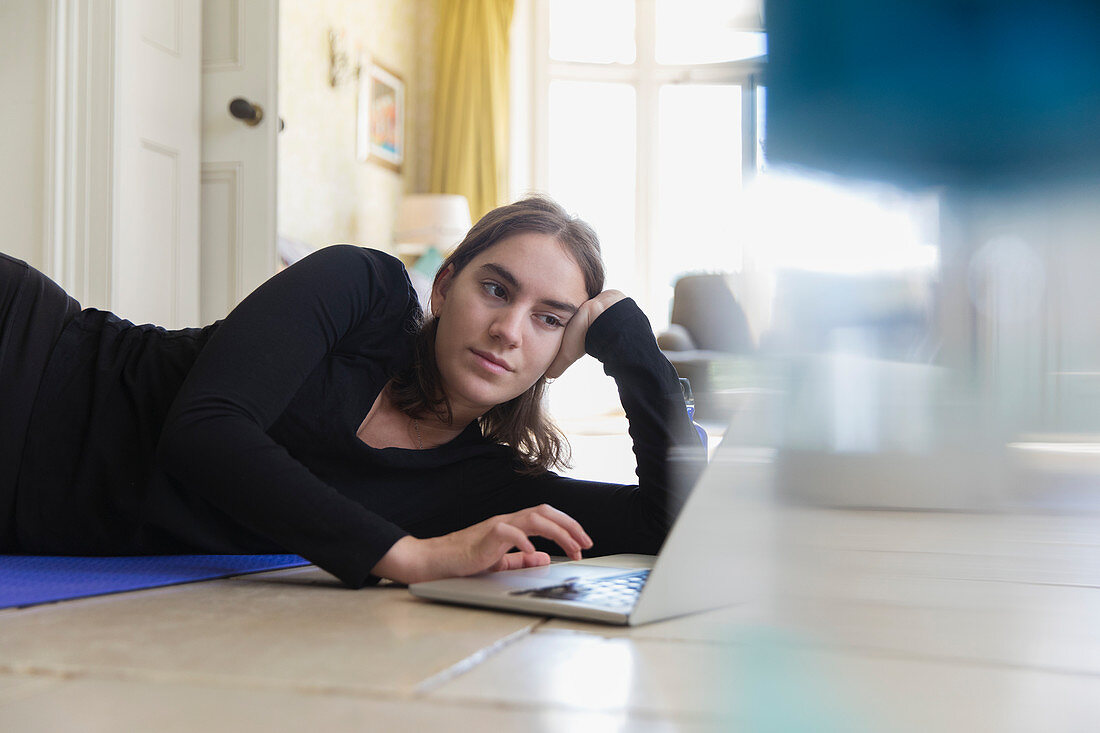Teenage girl practicing yoga at laptop from home