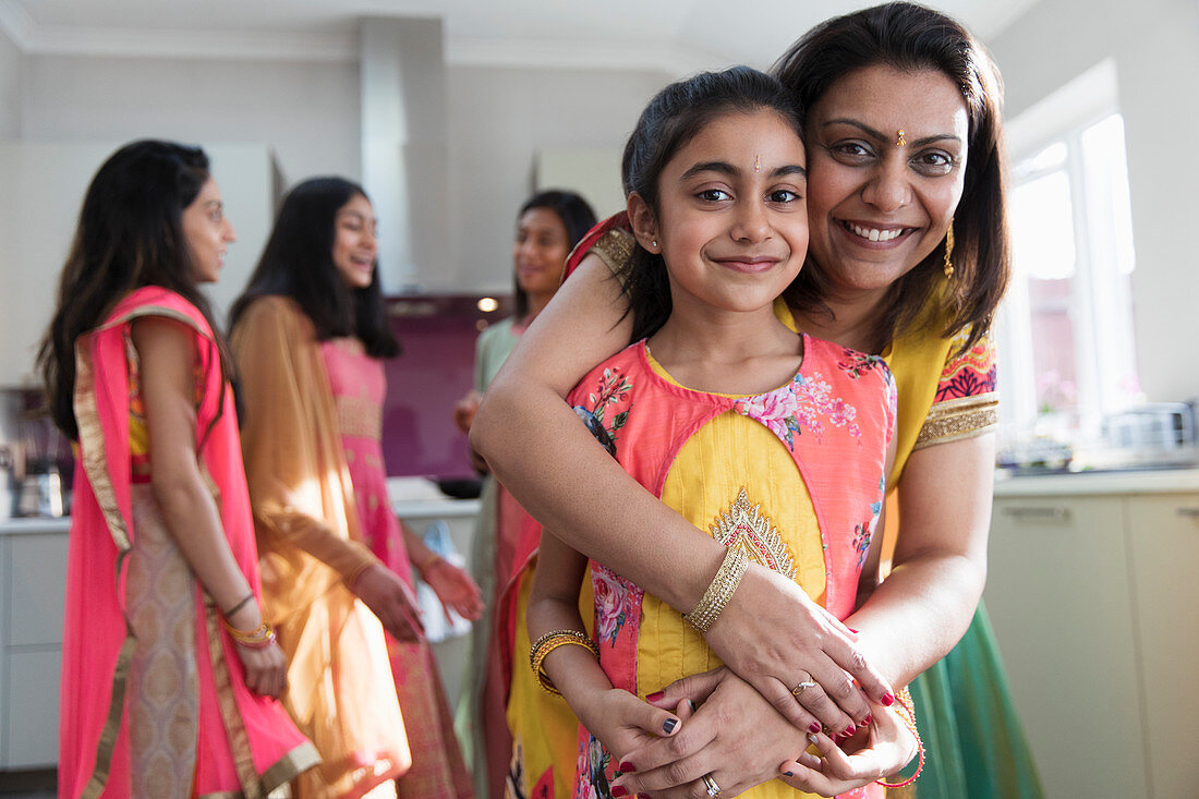 Portrait happy Indian mother and daughter in saris hugging