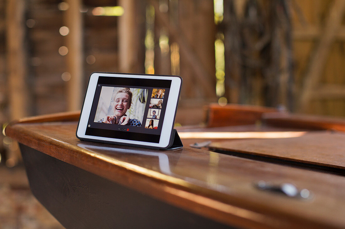 Friends video chatting on tablet screen on wooden boat