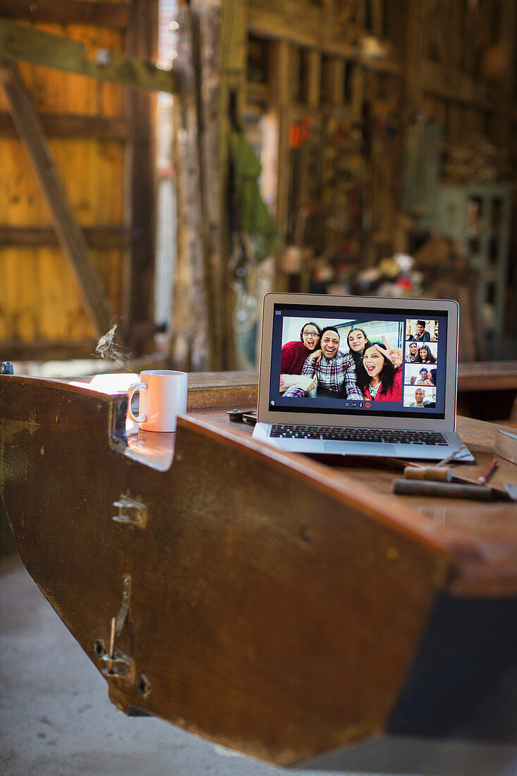 Friends video chatting on laptop screen on wooden boat