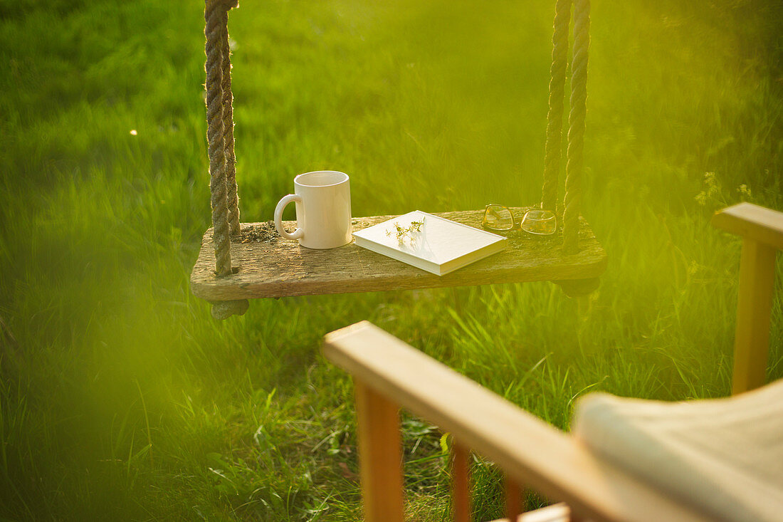 Coffee and book on swing in idyllic garden