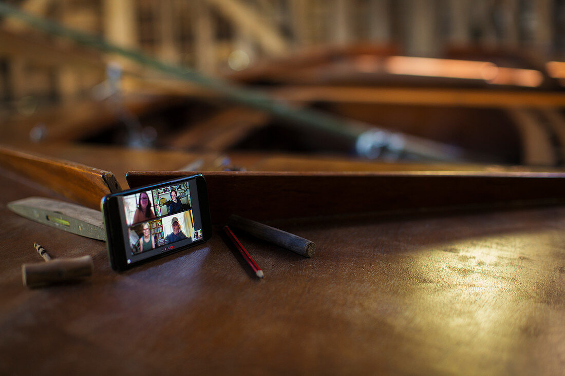 Colleagues video chatting on smart phone on wooden boat