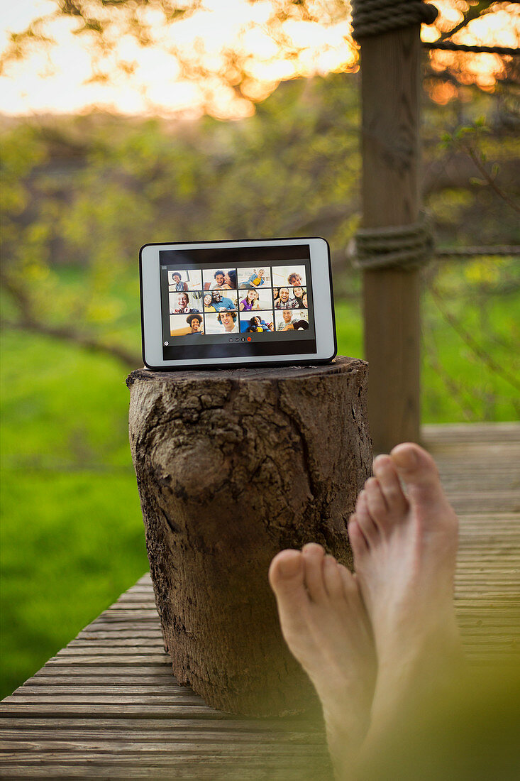 POV barefoot man video chatting with friends on tablet