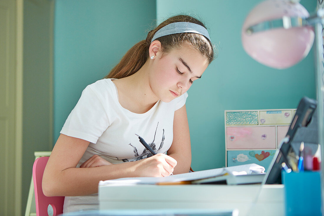 Girl doing homework at desk in bedroom