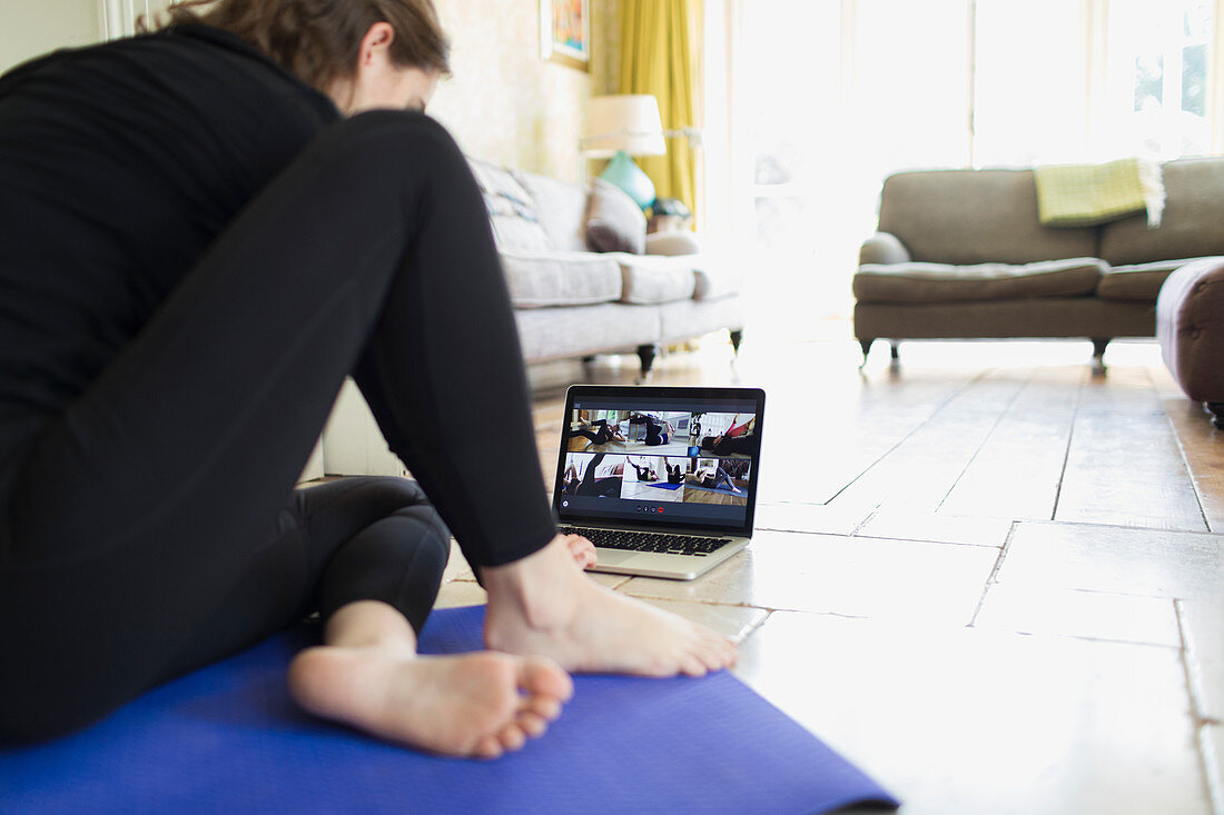 Woman taking online yoga class at laptop