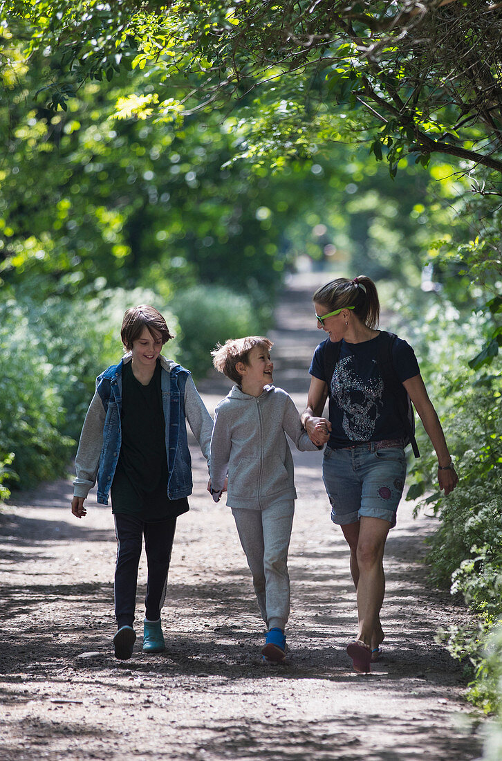 Mother and sons walking on sunny park path