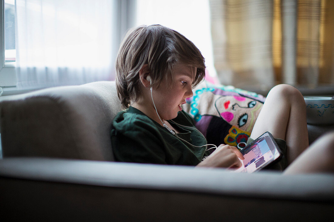 Boy with headphones using digital tablet in living room