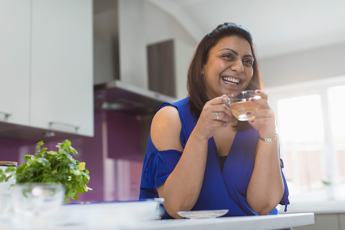 Happy woman drinking tea in kitchen