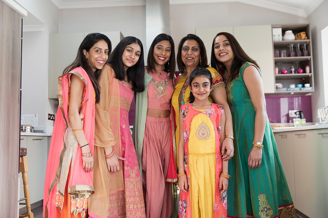 Portrait happy Indian women and girls in saris in kitchen