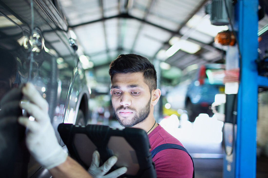 Focused male mechanic using digital tablet
