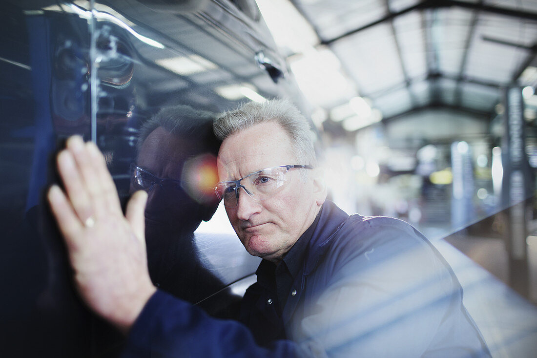 Focused male mechanic examining car