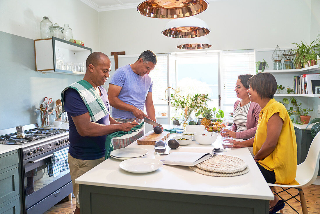 Mature wives watching husbands cook in kitchen