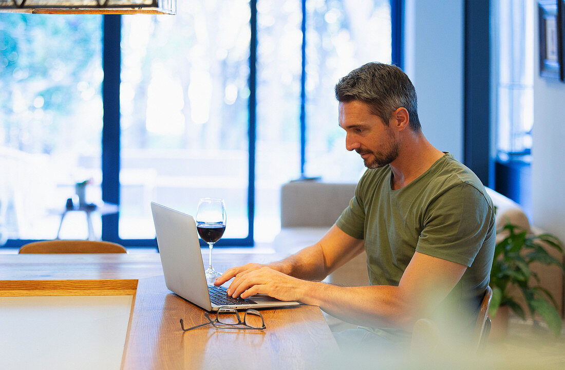 Man using laptop and drinking wine