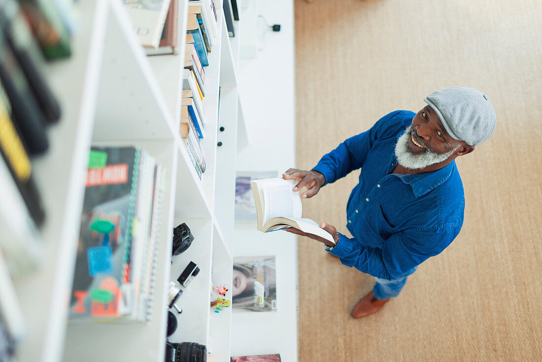 Portrait smiling man reading book at bookcase