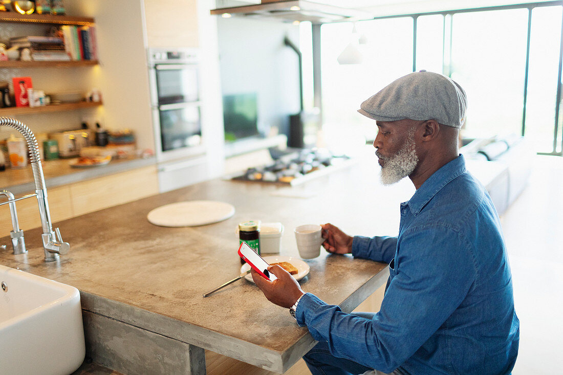Man enjoying breakfast and using smart phone