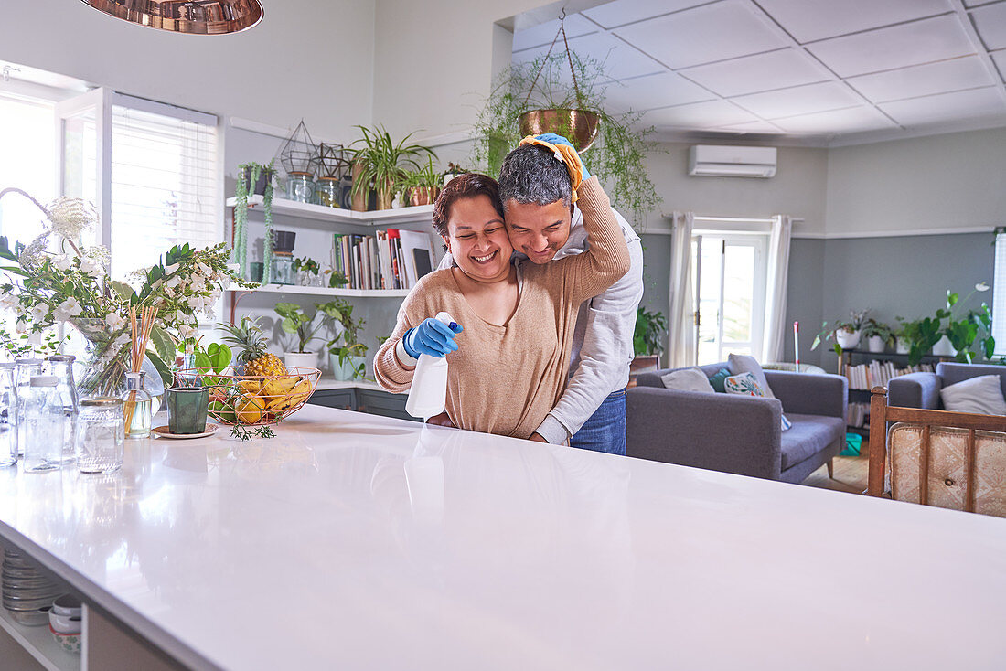 Mature couple hugging and cleaning kitchen island