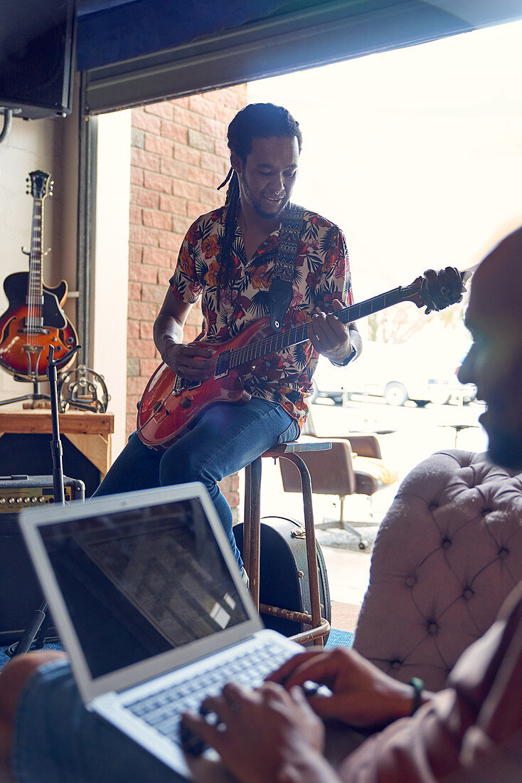 Male musicians with laptop and guitar practicing