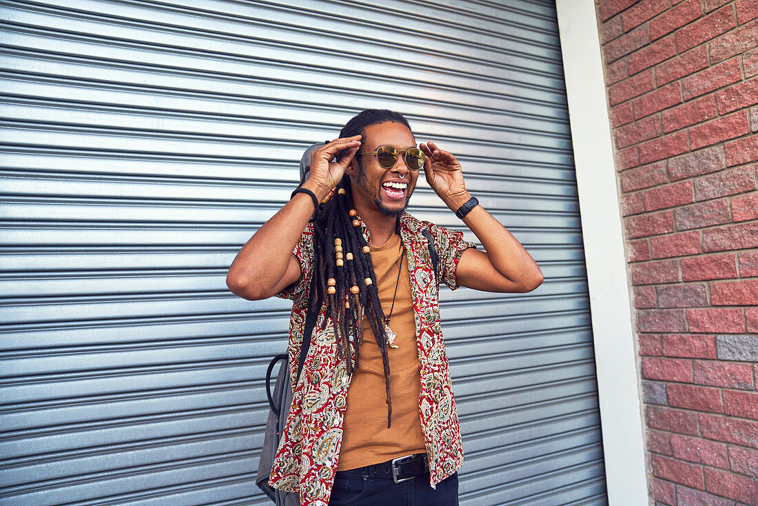 Man with dreadlocks and sunglasses outside garage