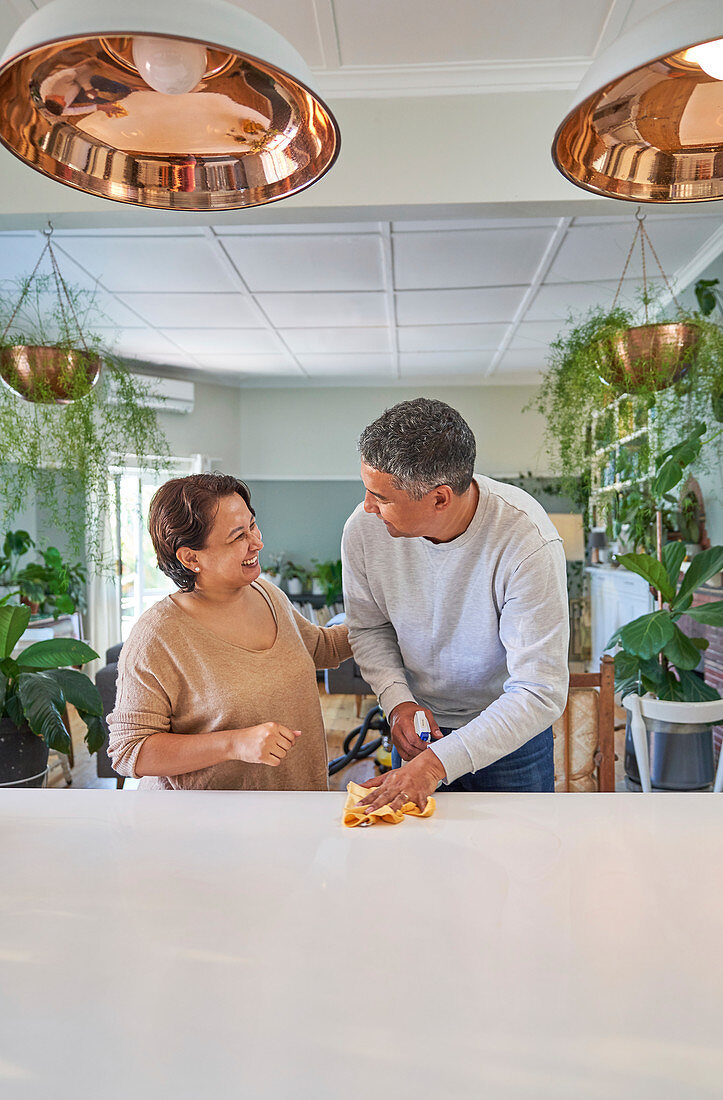 Mature couple cleaning kitchen island and talking