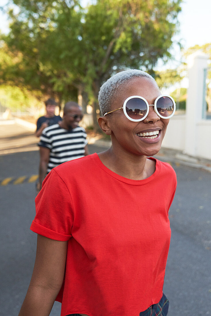 Happy young woman in sunglasses walking in street