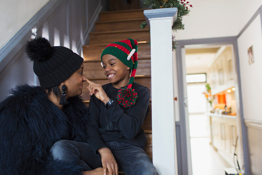 Playful mother and son in Christmas hat on stairs