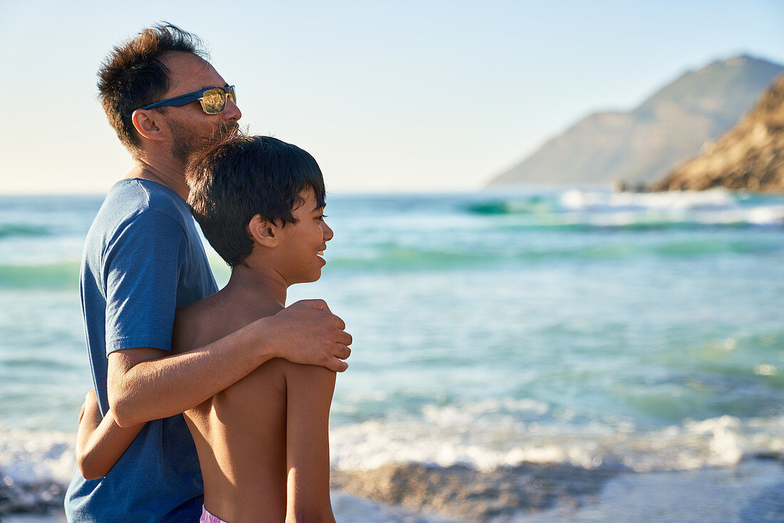 Affectionate father and son hugging on ocean beach